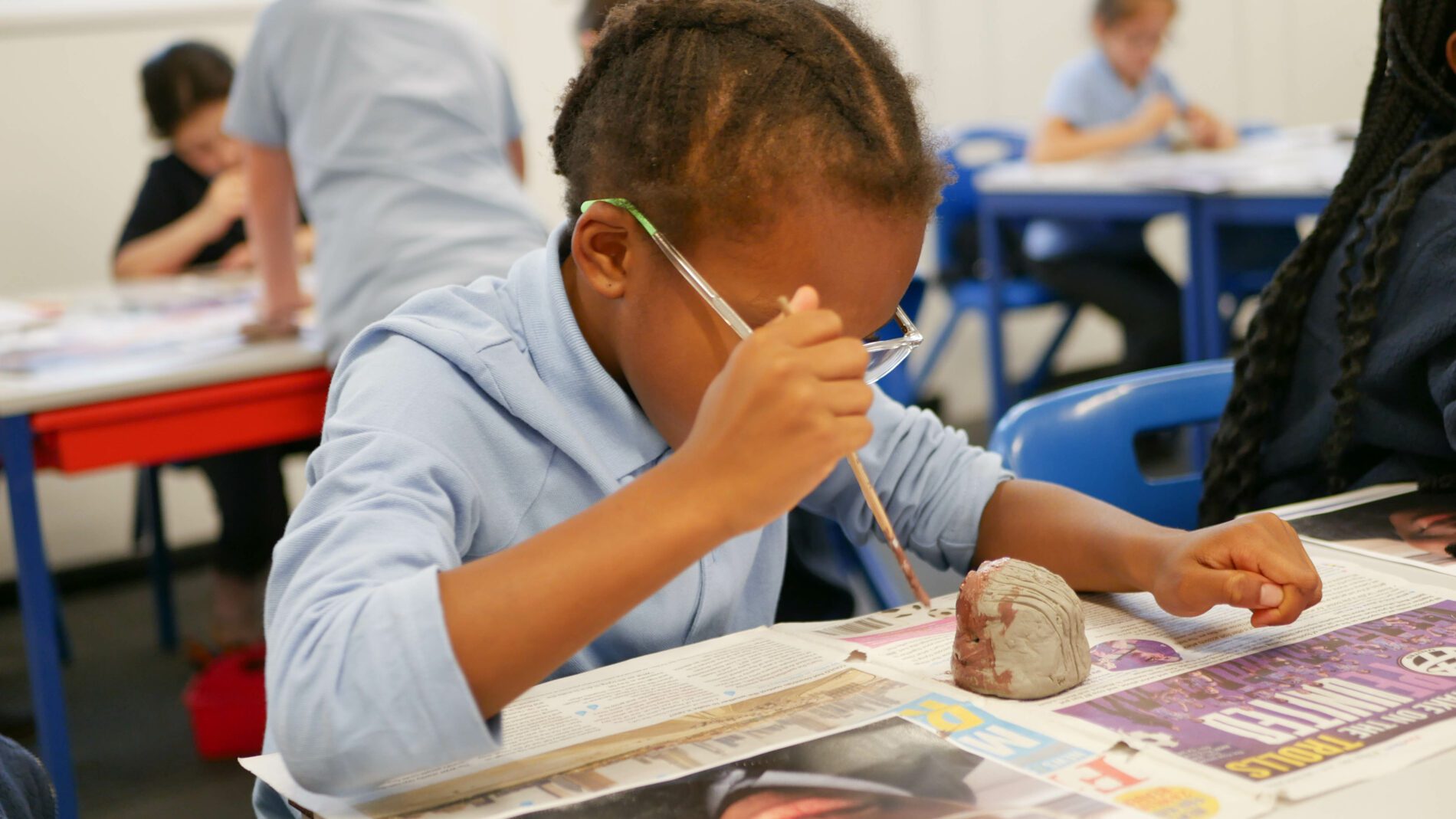 children in art class at rosherville academy painting clay sculptures