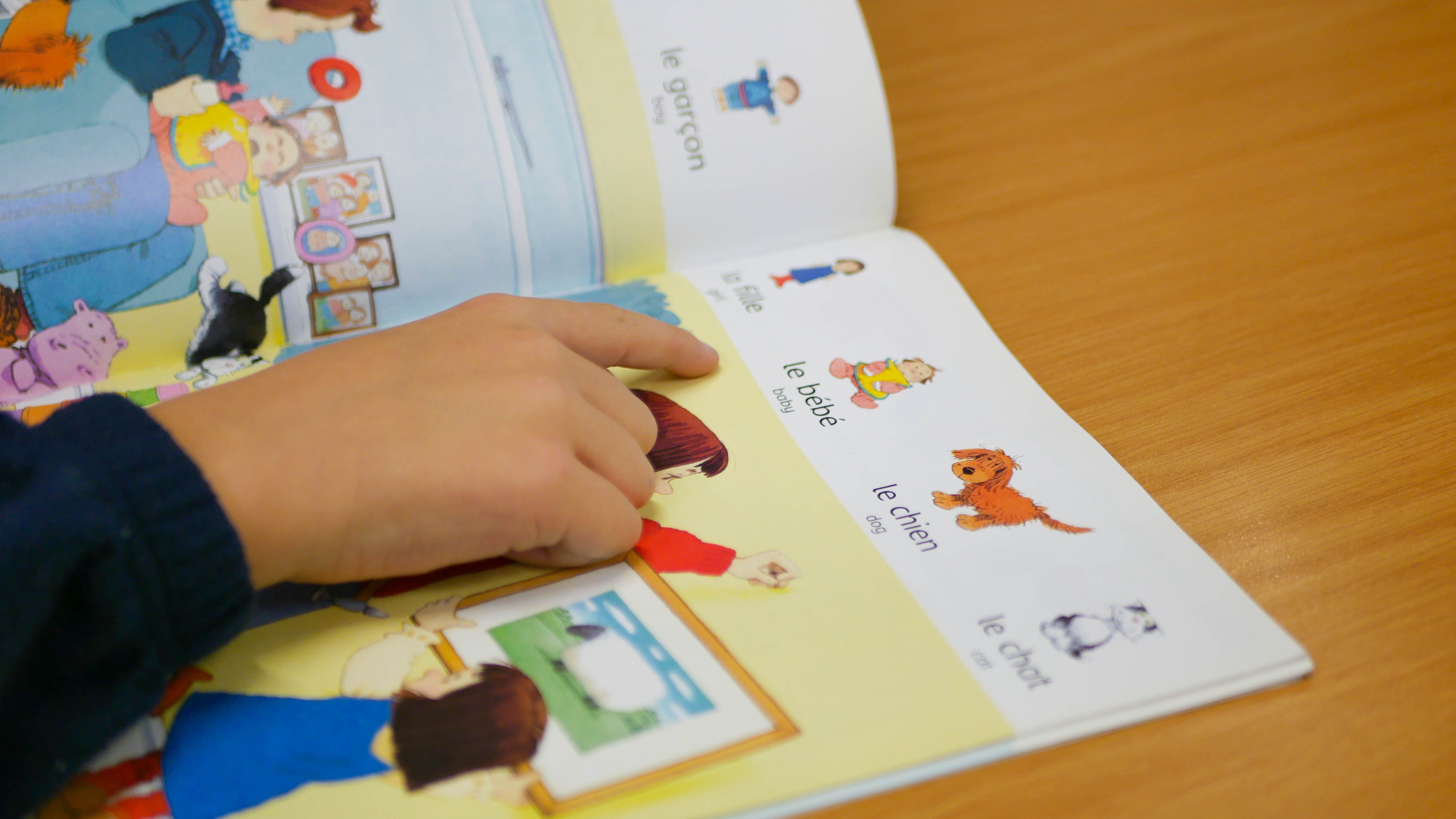 child pointing in a french book at rosherville academy